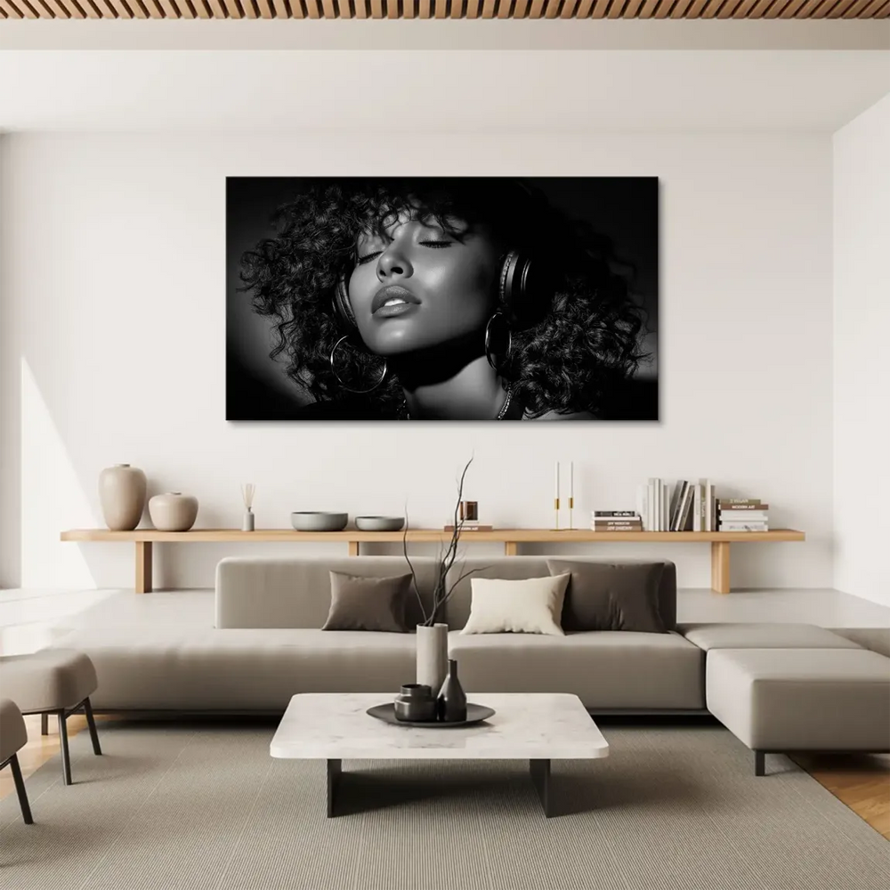 Monochrome photograph of a relaxed woman with curly hair, listening to music with eyes closed.