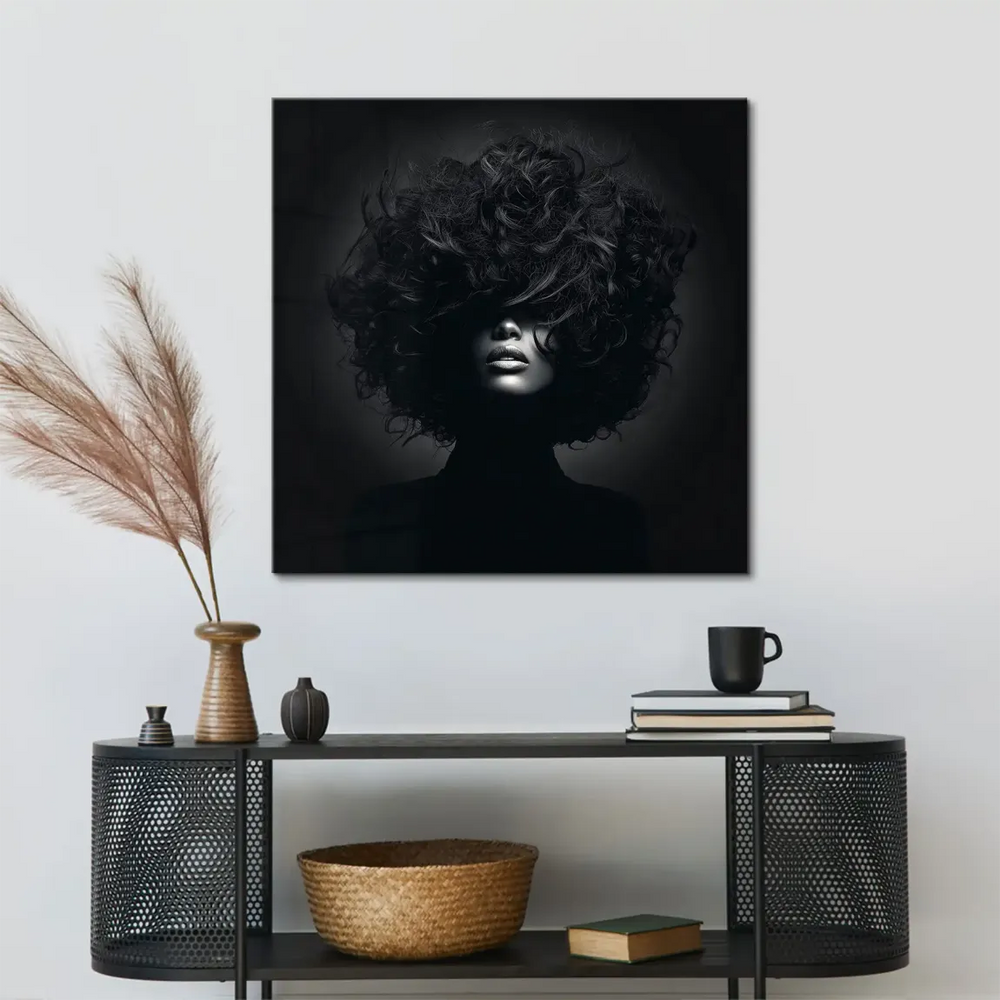 Close-up of illuminated lips and chin peeking through voluminous curls in a dramatic fashion photo.