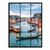 Twilight view of Venice Grand Canal through a black window-grid frame with gondolas and warm reflections on blue-green water.