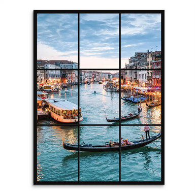 Twilight view of Venice Grand Canal through a black window-grid frame with gondolas and warm reflections on blue-green water.